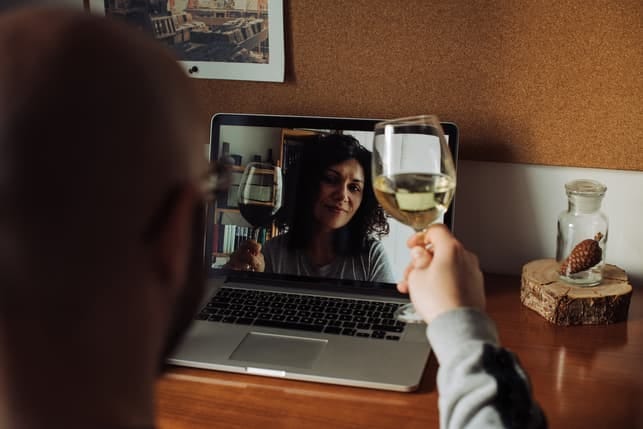 a couple is drinking wine while having a date via a video call