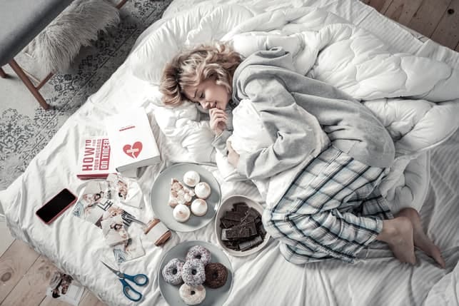 a girl is relaxing on her bed with cookies and candies
