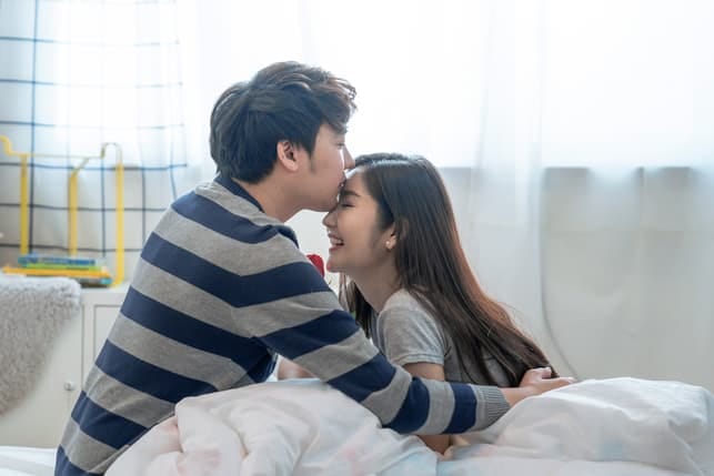 a man is kissing his girlfriend’s forehead