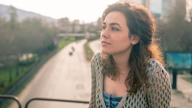 a young lady with curly hair looks away while being deep in her thoughts