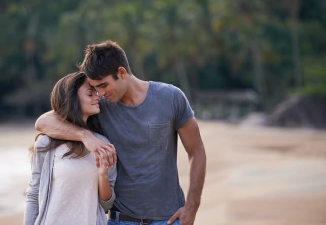 a young couple hugging and having a romantic walk on the seaside