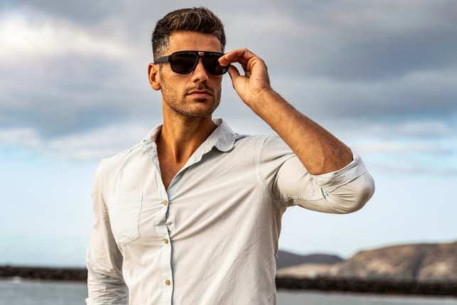 an attractive confident man wearing a white shirt and black sunglasses