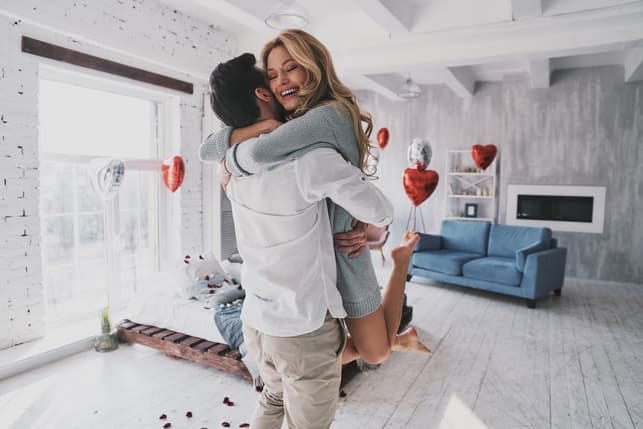 a woman is hugging her boyfriend happily at home