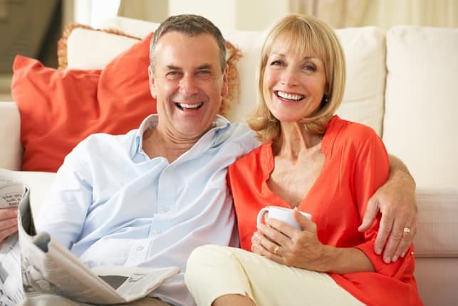 a happy mature couple posing together while sitting on a sofa