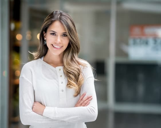 a confident woman is white is posing in a business centre while smiling