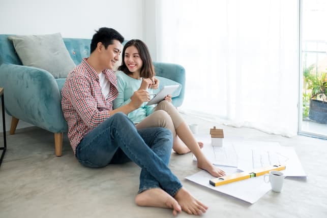 a happy Asian couple is hugging while sitting on the floor of their house