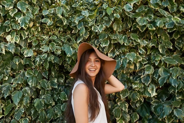 a young woman wearing a big hat posing outdoors